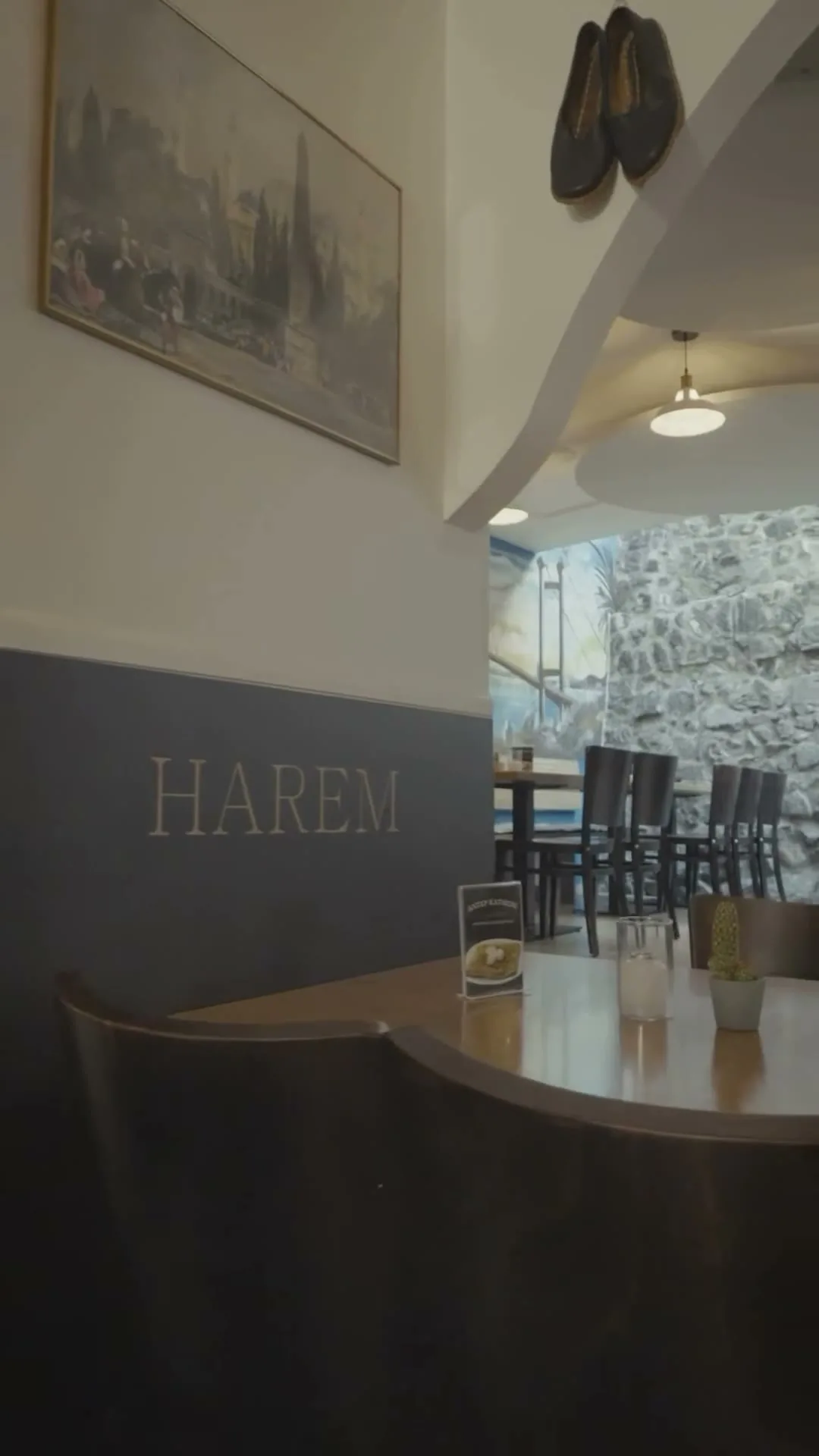 Gastraum des Restaurants Harem: HAREM-Schriftzug an der Wand, Istanbul-Gemälde und Blick auf die historische Steinmauer