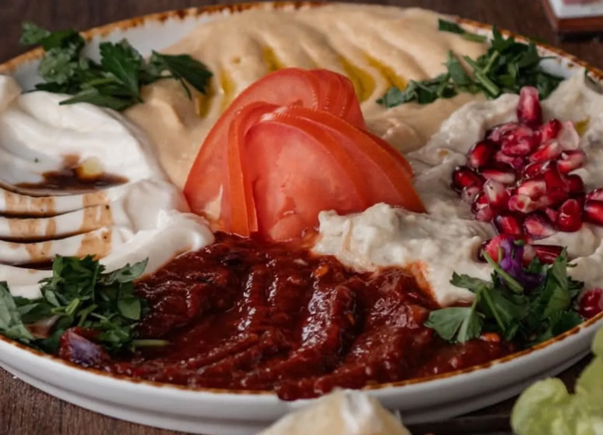 Meze-Teller mit Hummus, Joghurt-Dips, Tomaten und Granatapfelkernen